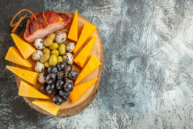 Above view of delicious snack including fruits and foods for wine on a brown tray on gray background