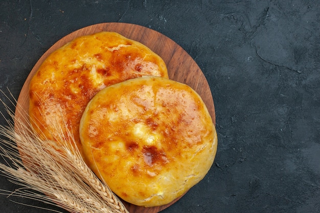 濃い黒地にある木製のまな板のおいしい焼きたてのペストリーとスパイクのビューの上