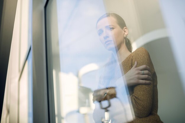 Free photo below view of depressed woman looking through the window
