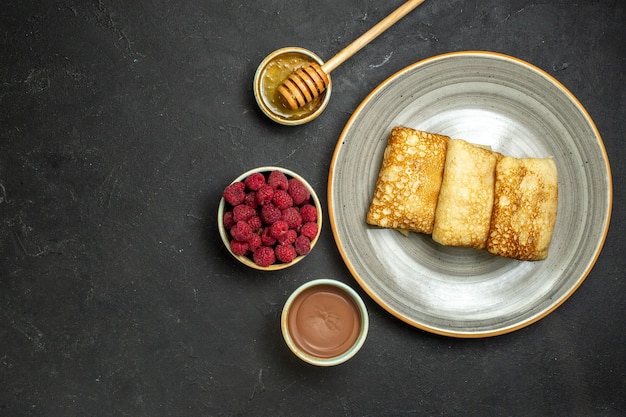 Foto gratuita sopra la vista dello sfondo della cena con deliziose frittelle al miele e lampone al cioccolato su sfondo nero