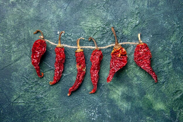 Above view of dried red peppers tied up with rope on green black mixed colors table with free space