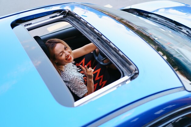 View of a driving woman through sunroof