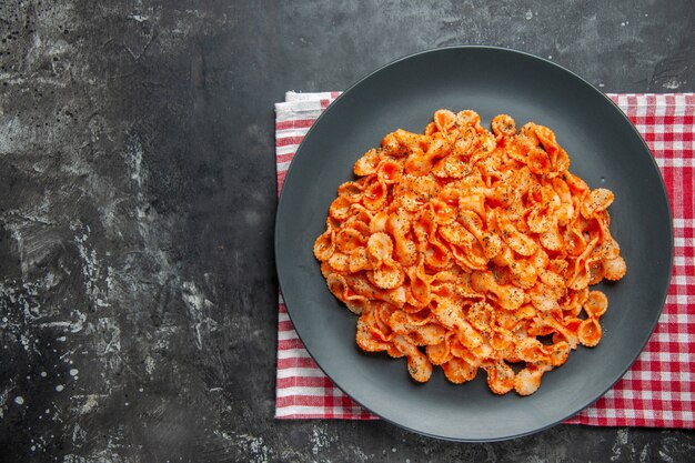 赤い皮をむいた布の黒い皿の上にある、夕食の簡単なパスタ料理