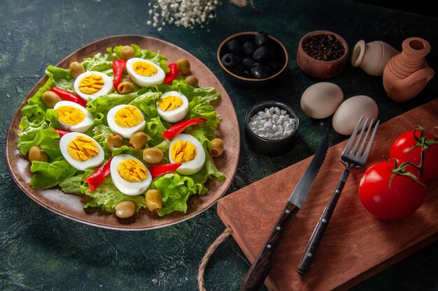 above view egg salad consists of olives and green salad on dark blue background