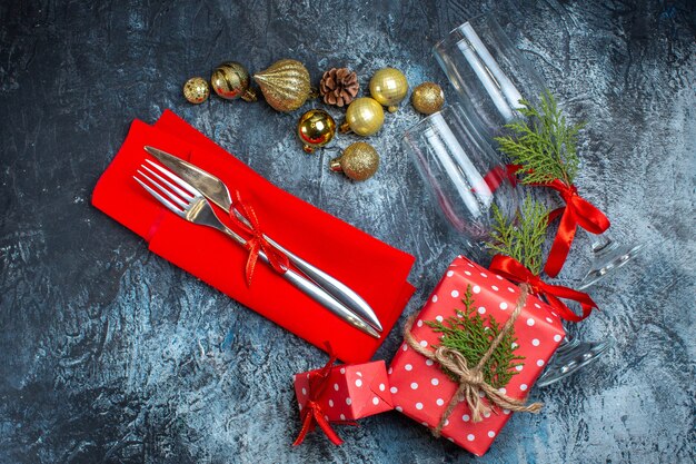 Above view of fallen glass goblets and cutlery set decoration accessories gift box and christmas sock on dark table