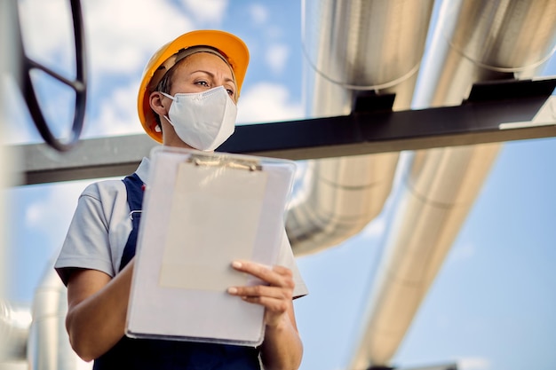 Free photo below view of female inspector wearing protective face mask at construction site