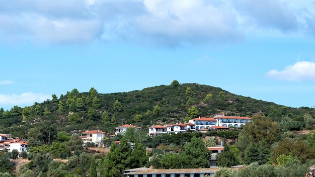 View of a few building made in identical style on a hill covered with lush greenery in Ouranoupolis, Greece