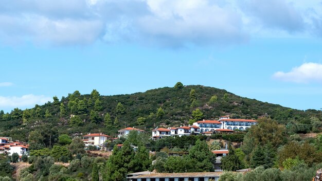 View of a few building made in identical style on a hill covered with lush greenery in Ouranoupolis, Greece