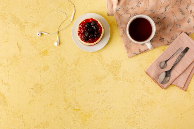 Above view frame with food and headphones on yellow background