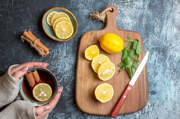 Above view of fresh lemons and mint knife on a wooden cutting board