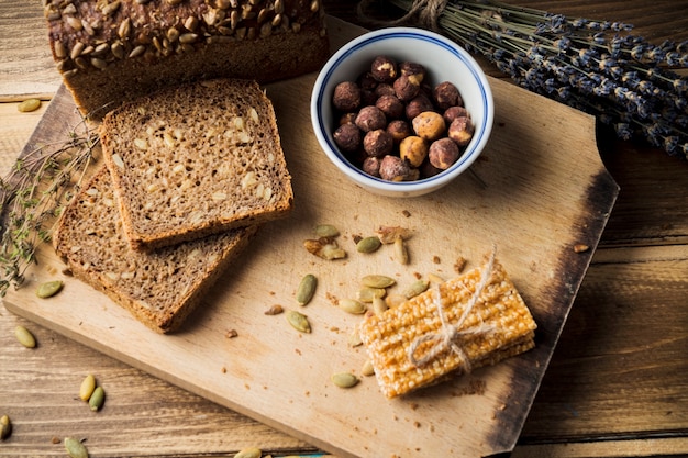 To view of fresh organic bread with ingredients and energy bar on chopping board