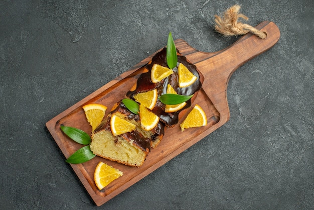 Above view of freshly baked soft cake slices on wooden cutting board on dark table