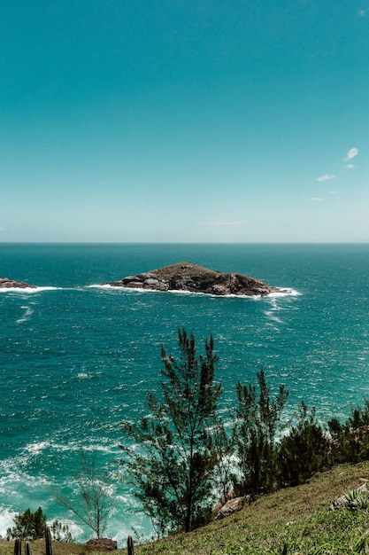 View from a cliff seeing a small island surrounded by sea on a clear sky scene