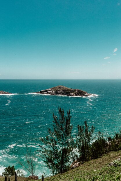 View from a cliff seeing a small island surrounded by sea on a clear sky scene