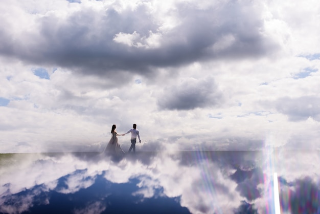 View from distance newlyweds walk in the clouds