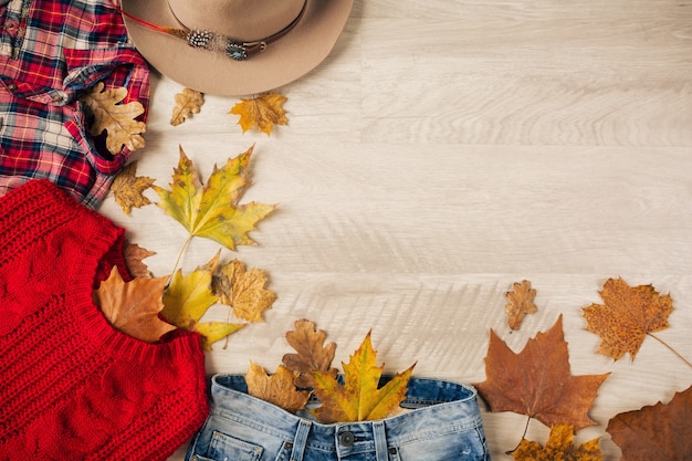 Free photo view from above on flat lay of woman style and accessories, red knitted sweater, checkered flannel shirt, denim jeans, hat, autumn fashion trend, traveler outfit
