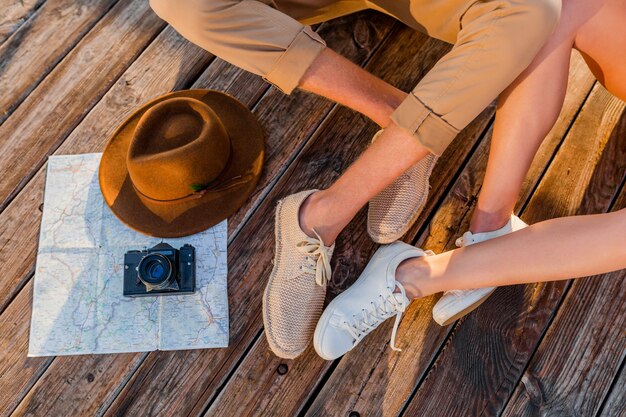 Вид сверху ноги пары, путешествующей летом, одетой в кроссовки