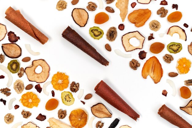 View from above of neatly stacked fruit lozenge different colors and almonds, orange, dried apricot, raisins, walnuts, dried apples and kiwi on white background. Concept of healthy snacks.