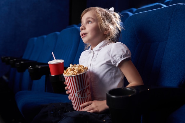 View from side of girl watching excited movie in cinema