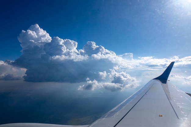 Вид из окна самолета на крыло самолета на фоне голубого облачного неба и яркого солнца. место для вашего текста. концепция путешествий и туризма.