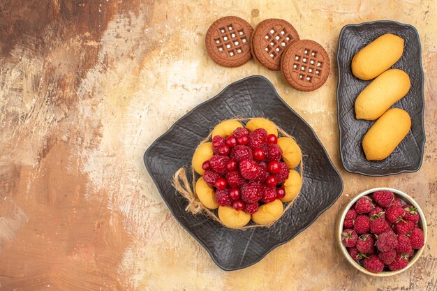 Above view of a gift cake and biscuits on brown plates on mixed color table