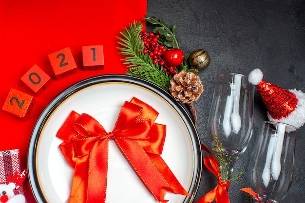 빨간 리본 디너 플레이트 장식 액세서리 전나무 가지 크리스마스 양말 유리 받침 어두운 테이블에 산타 클로스 모자와 선물보기 위