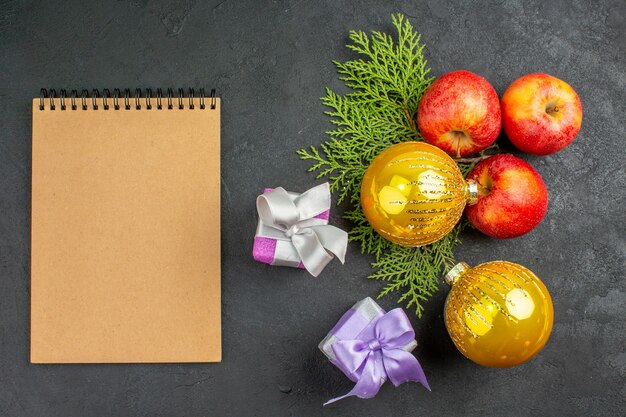 Выше вид подарков и аксессуаров для украшения натуральных органических свежих яблок и ноутбуков на черном столе