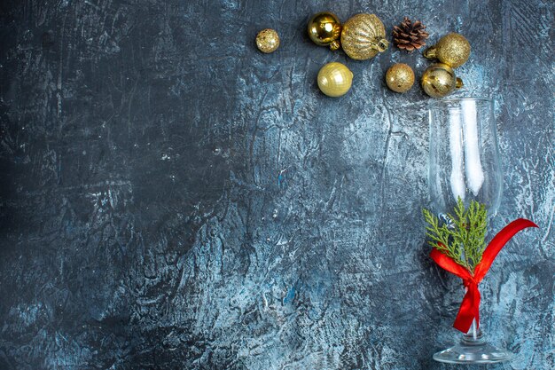 Above view of glass goblet with red ribbon and decoration accessories on dark background