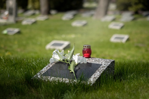 View of gravestone with flowers and candle
