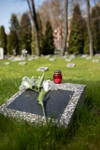 View of gravestone with flowers and candle