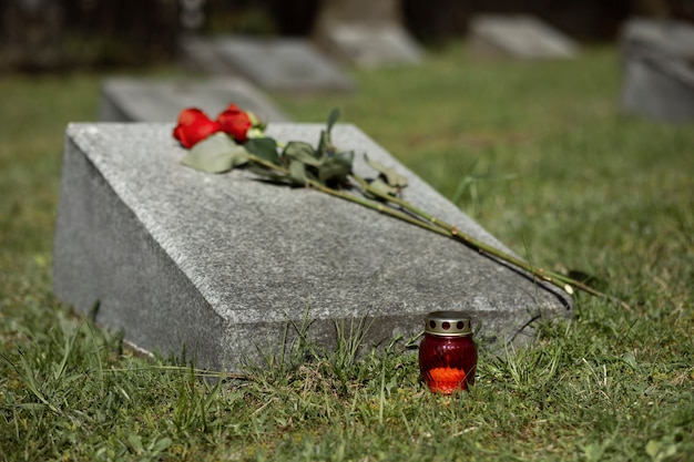 Free photo view of gravestone with flowers and candle