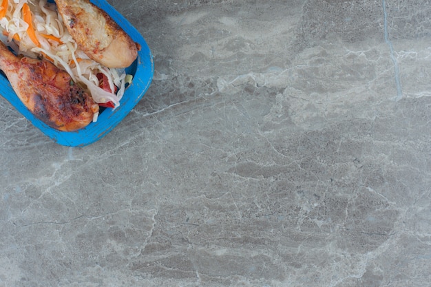 To view of grilled chicken legs with sauerkraut on wooden board. 