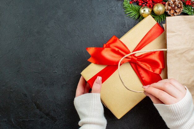 Above view of hand holding a beautiful gift box on dark background