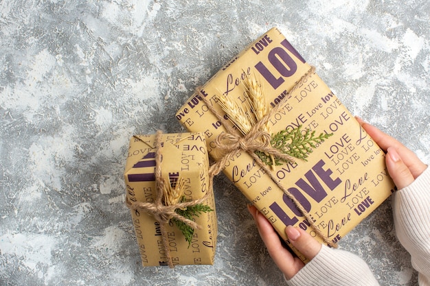 Above view of hand holding beautiful packed gift for Christmas on ice surface