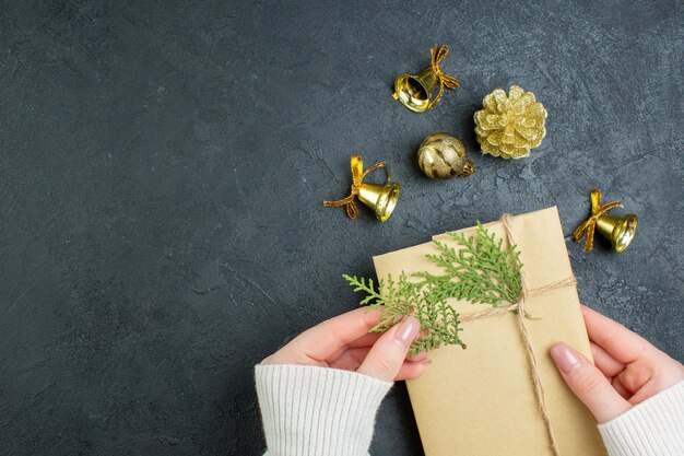 Above view of hand holding gift box and decoration accessories on dark background