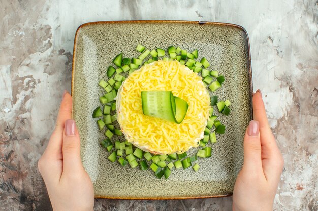 混合色の背景に刻んだキュウリを添えておいしいサラダを手に持ってのビューの上