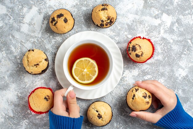 氷の表面にお茶とチョコレートとおいしい小さなカップケーキの1つを持って取っている手のビューの上