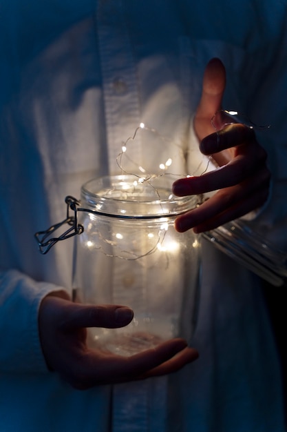 Free photo view of hands holding jar of lights