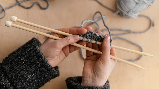 Above view hands holding knitting needles