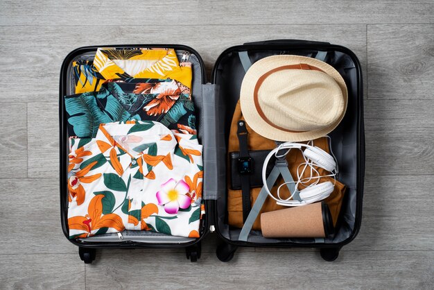 View of hawaiian shirts stacked in luggage with hat and headphones