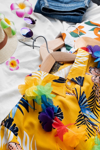 Foto gratuita veduta di camicie hawaiane con stampa floreale su grucce e occhiali da sole