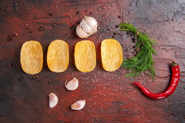 Above view of homemade delicious four crispy chips red pepper garlic green on dark background