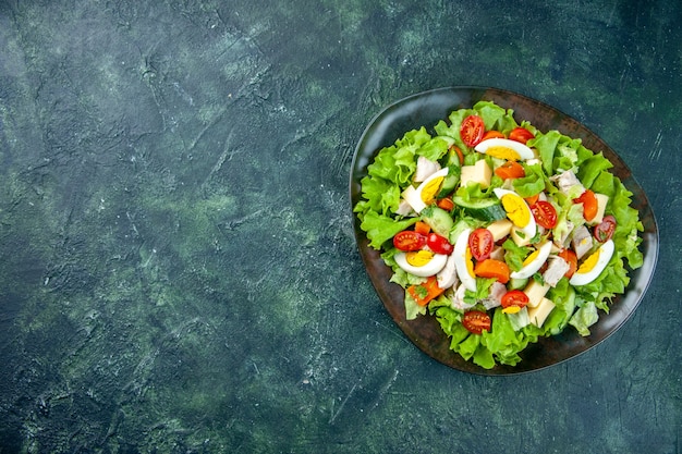 여유 공간이있는 녹색 검은 색 혼합 색상 테이블의 왼쪽에 검은 접시에 수제 맛있는 샐러드보기 위