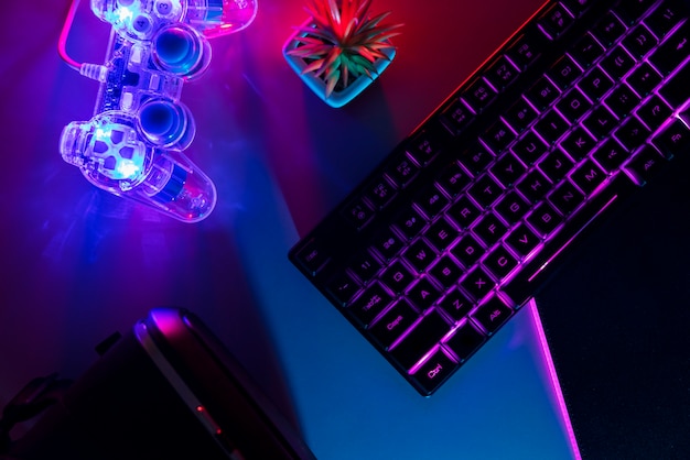 View of illuminated neon gaming keyboard setup and controller