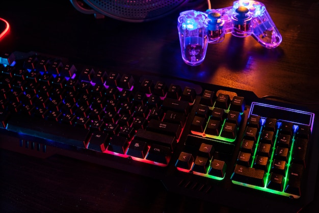 View of illuminated neon gaming keyboard setup and controller