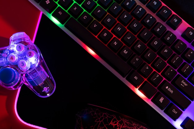 View of illuminated neon gaming keyboard setup and controller