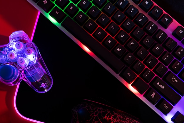 Вид на игровую клавиатуру с неоновой подсветкой и контроллер
