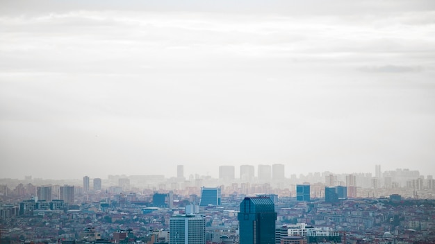 Вид на Стамбул в пасмурную погоду, несколько высоких и низких зданий, туман, Турция