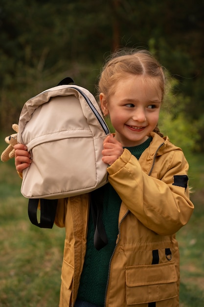 View of little girl with backpack adventuring in nature