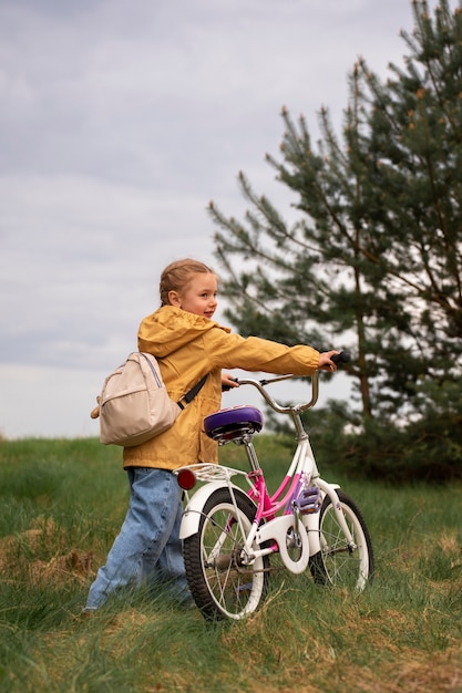 バックパックと自転車で自然の中で冒険する少女の眺め